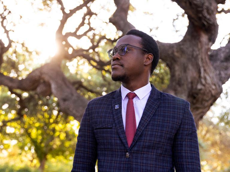 Student, Emmanuel Epau, poses in front of Sorin Oak